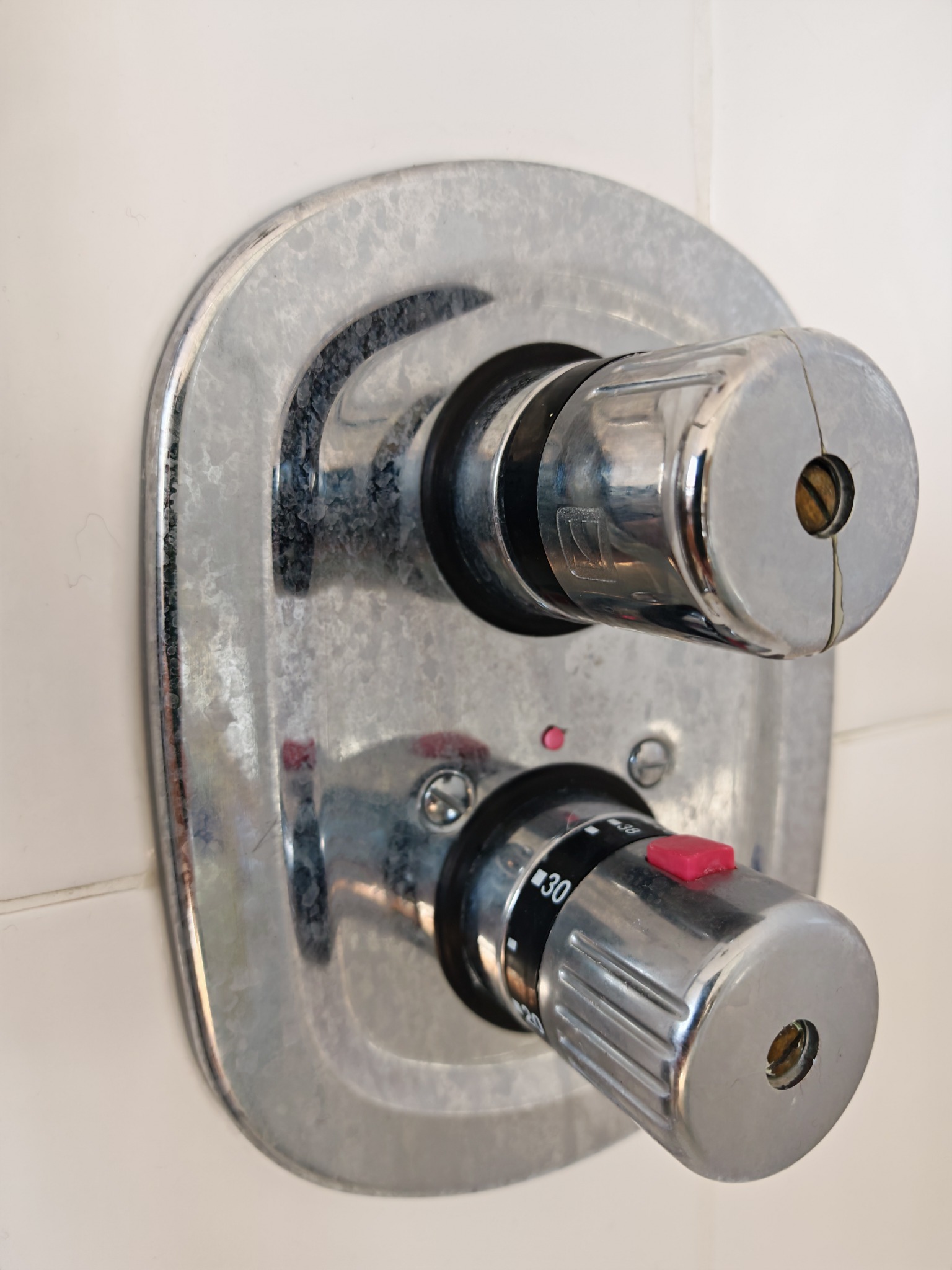 Chrome shower controls with heavy limescale before cleaning