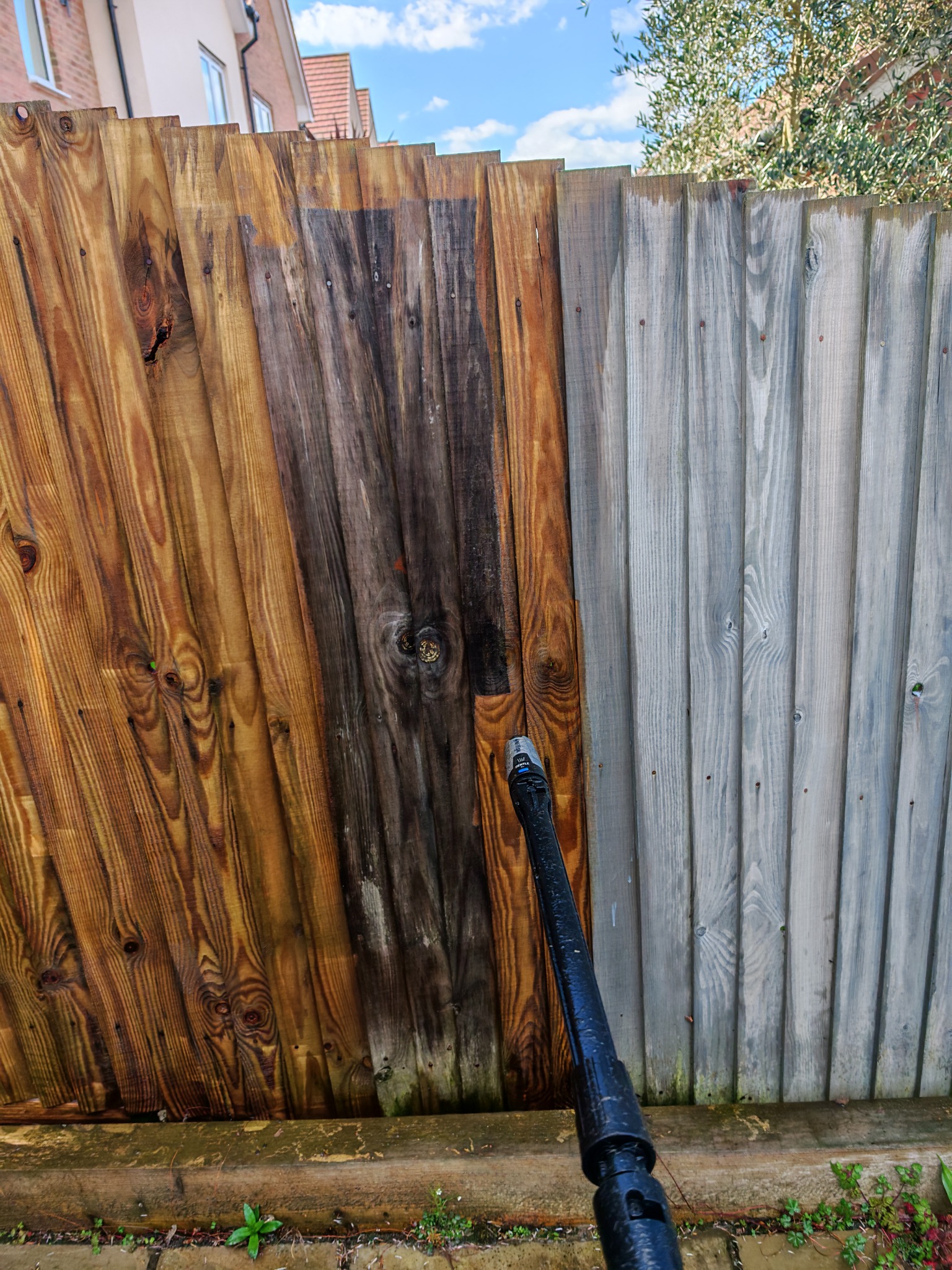Wooden fence being pressure washed
