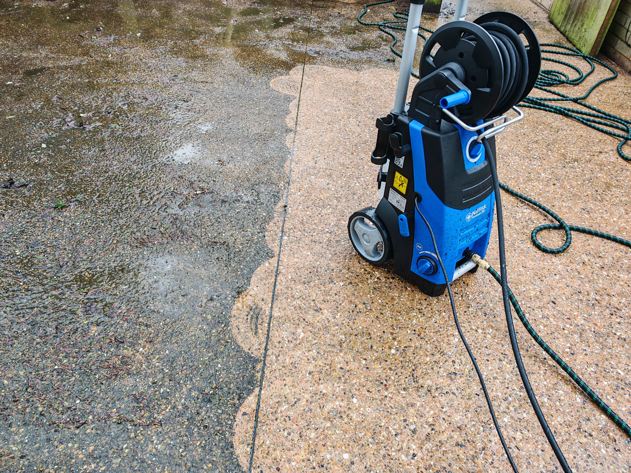 Pressure washing in progress with a clear clean line across the patio